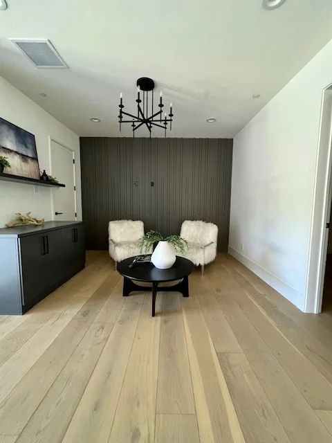 Light oak wide-plank hardwood flooring in modern living room with dark accent wall