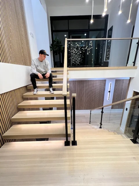Modern wooden staircase with black metal railings and light wood flooring in contemporary interior space