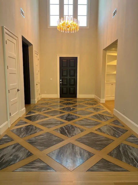 Geometric marble foyer with brass diamond lattice inlay pattern and high ceiling