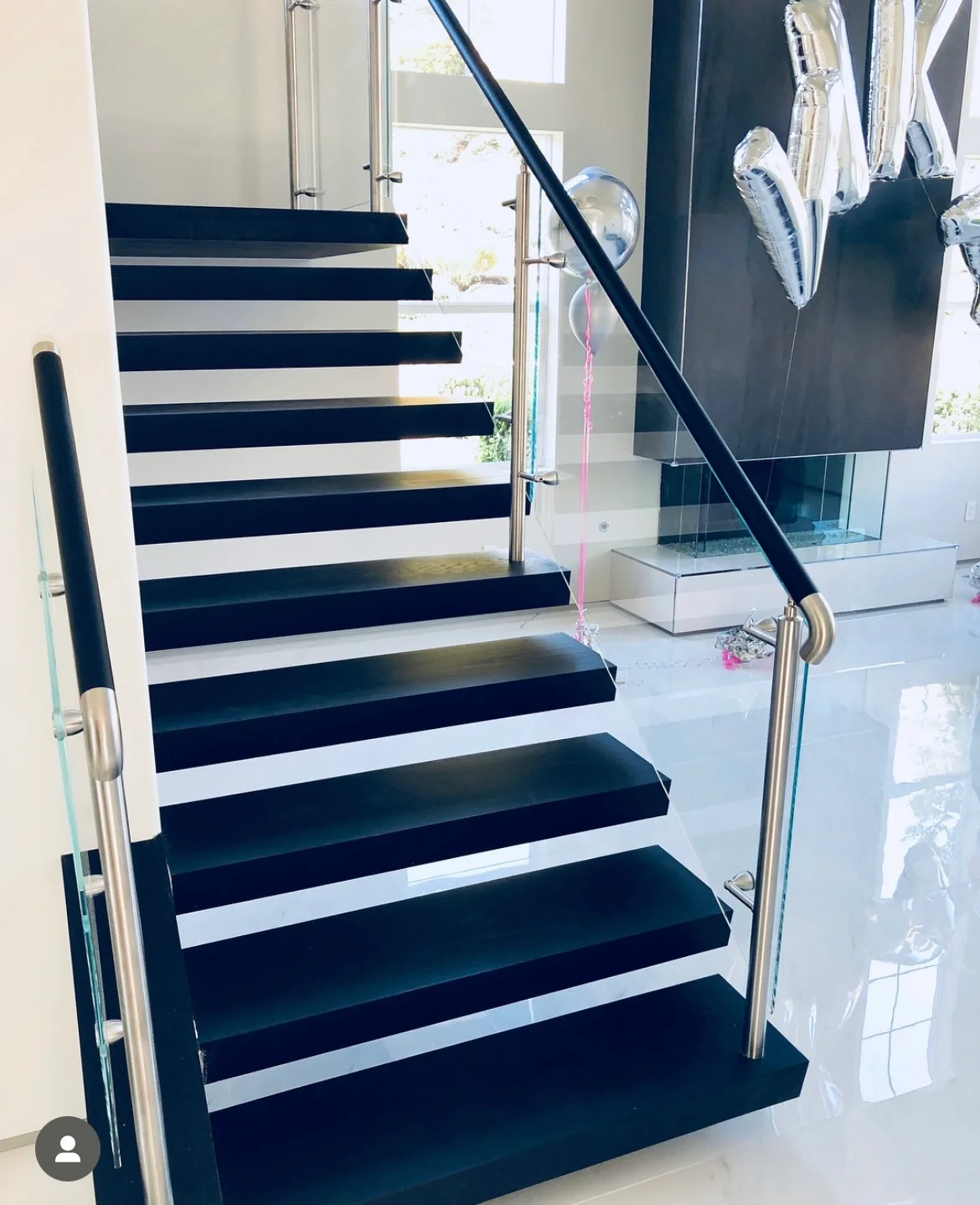 Modern staircase with navy and white striped steps, stainless steel handrail, and glass railing panels