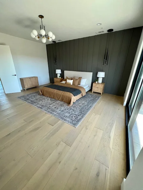 Light oak hardwood flooring installed in modern bedroom with dark accent wall