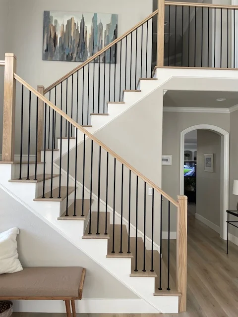 Custom staircase with white steps, natural wood rails, and black metal balusters