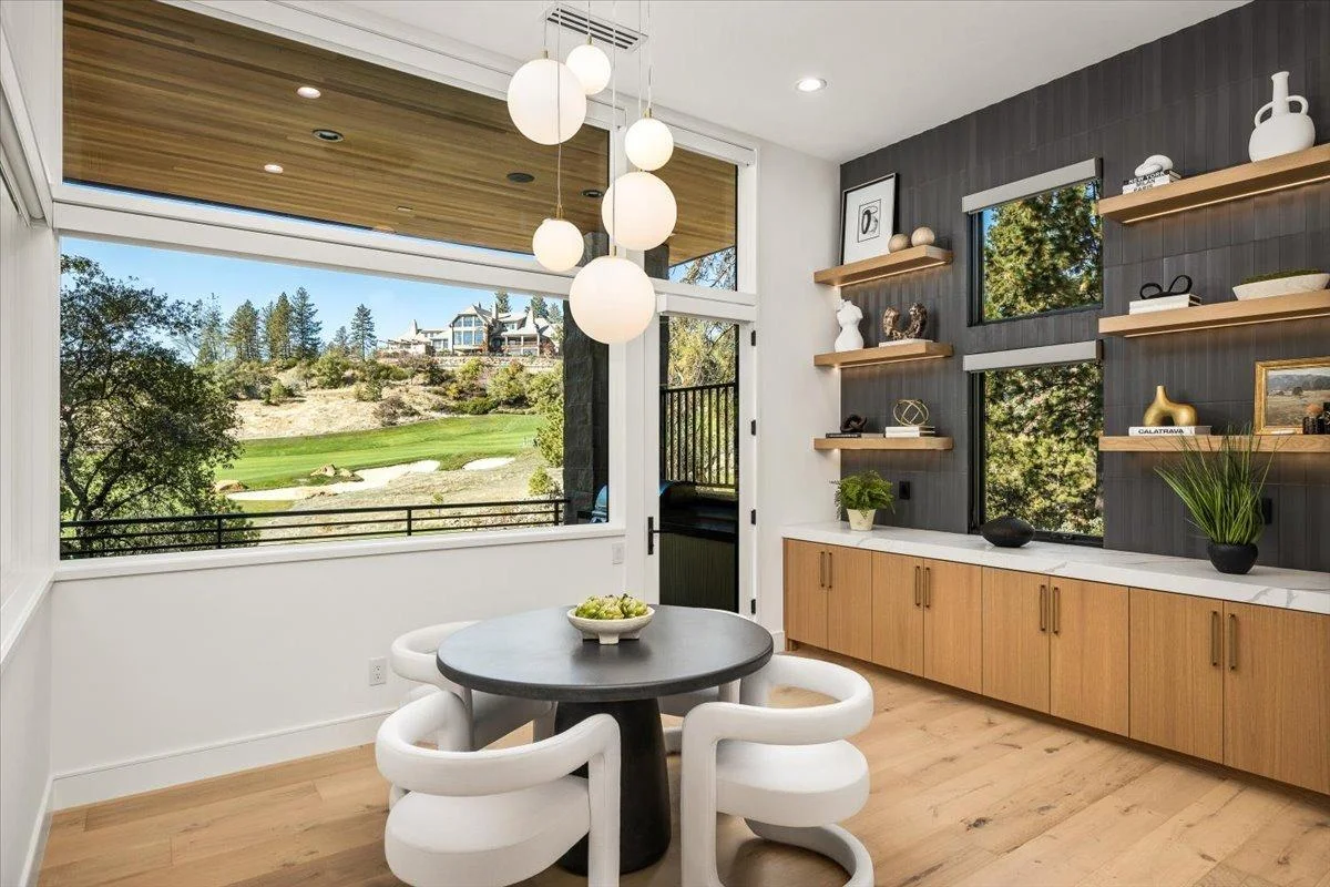 Modern living room with wide-plank hardwood flooring, pendant lighting, and panoramic windows