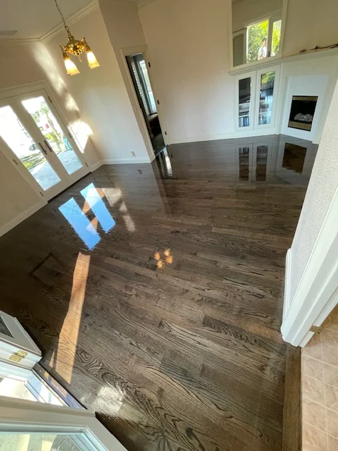 Dark hardwood flooring installed in bright open living room with white walls and trim