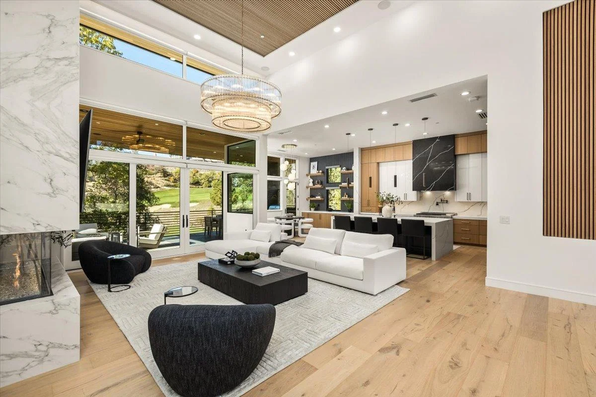 Modern living room with wide-plank hardwood flooring, white sofa, and marble accents