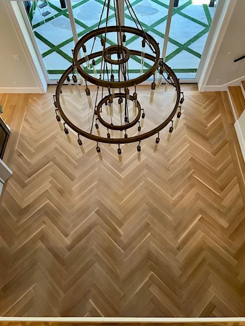 Herringbone hardwood floor with overhead skylight and decorative chandelier