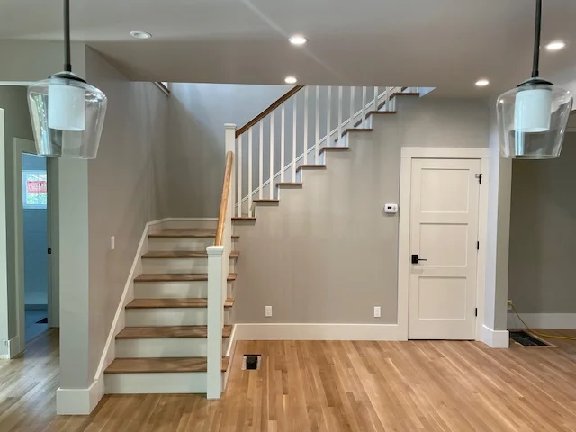 Hardwood flooring in basement with custom staircase and white trim